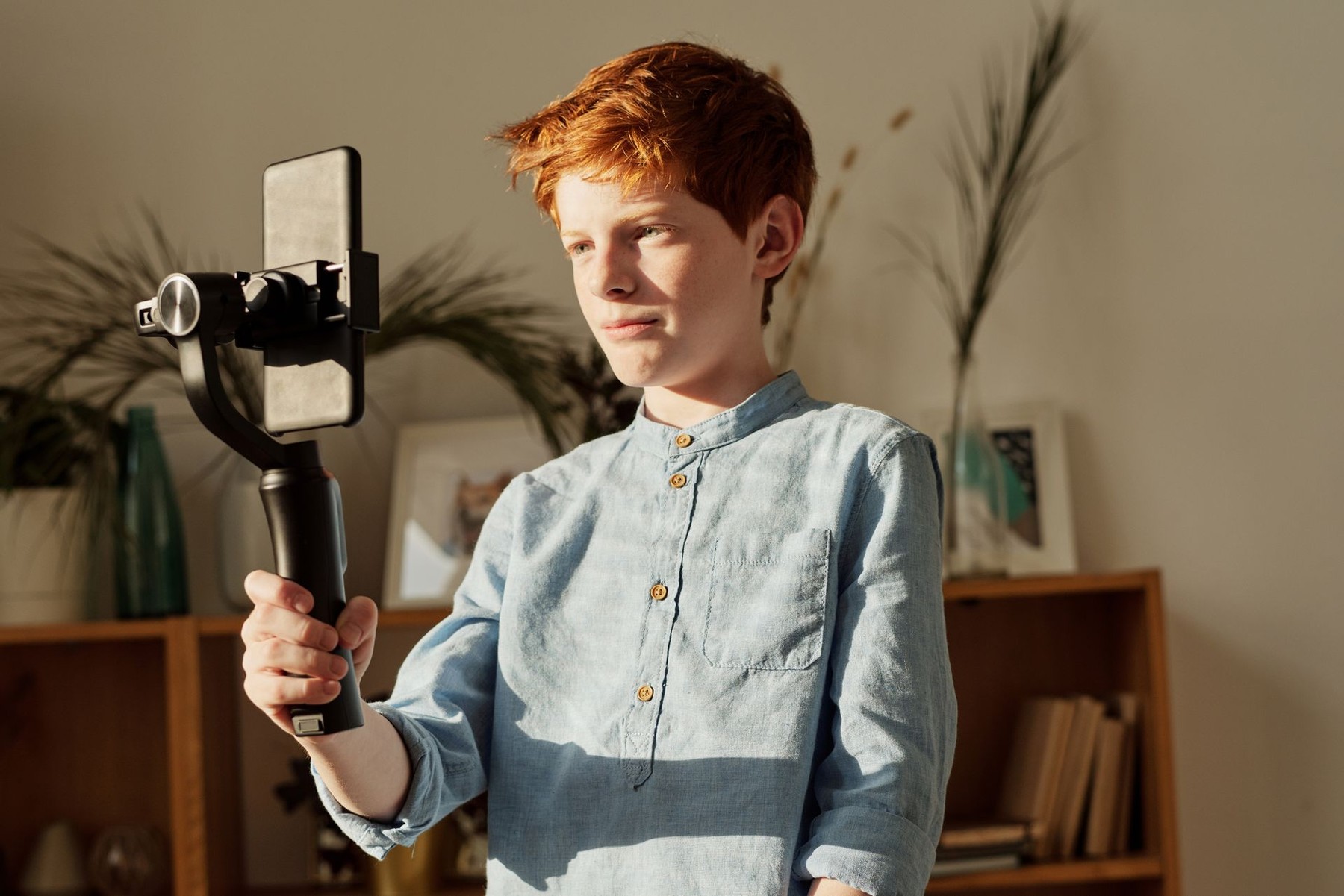 Young creator recording a video on a handheld smartphone gimbal